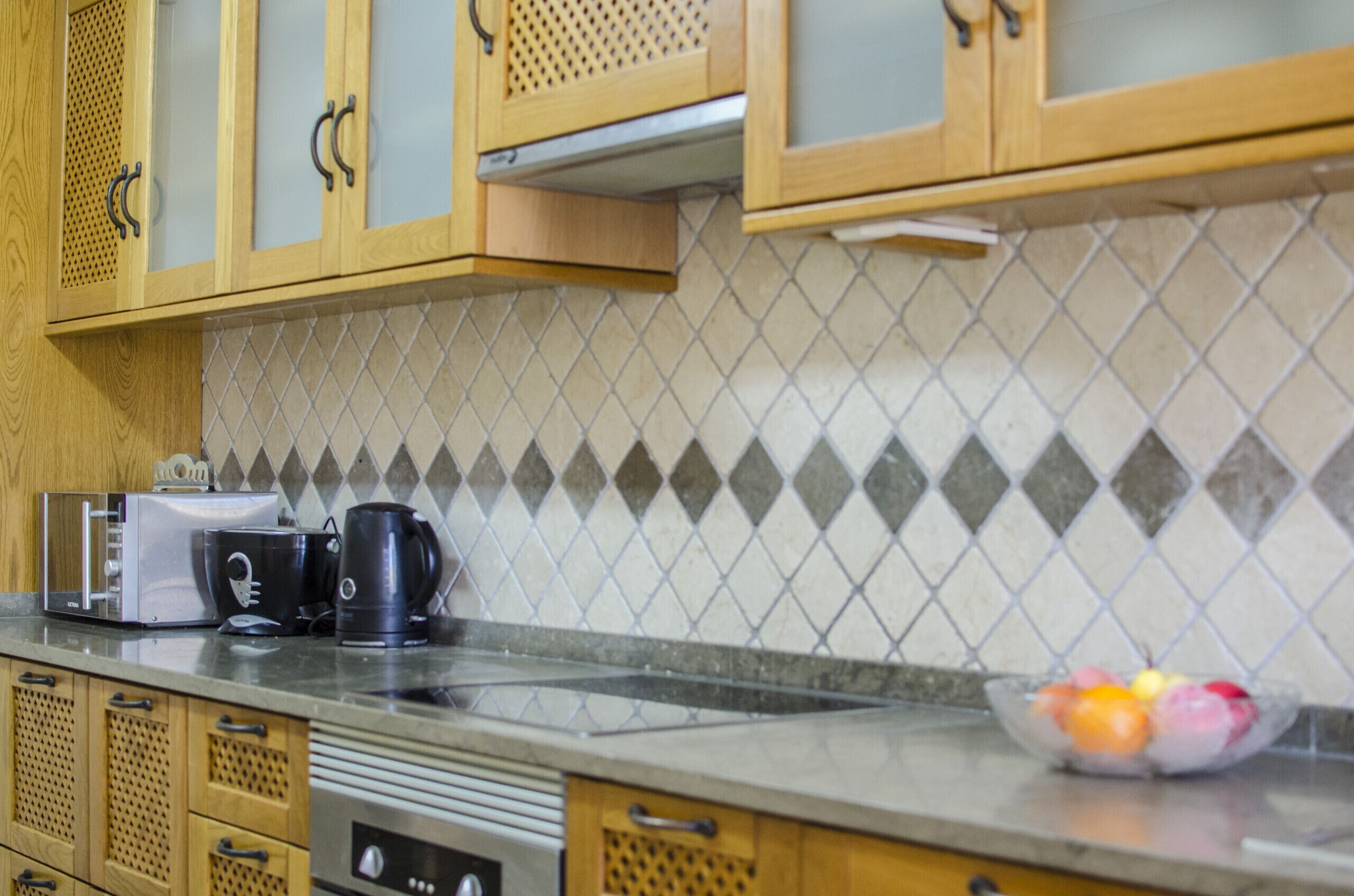 A kitchen with wooden cabinets, a microwave, a toaster, and a coffee maker on the counter.