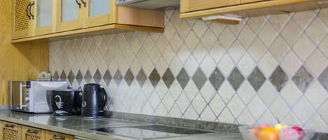 A kitchen with wooden cabinets, a microwave, a toaster, and a coffee maker on the counter.