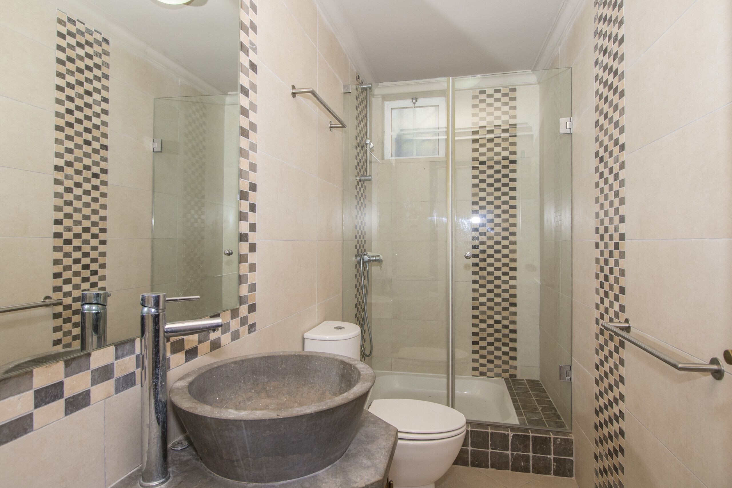 Une salle de bain avec un grand lavabo en pierre, une douche à parois de verre et des toilettes.