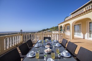 Una mesa de comedor dispuesta con platos, tazas y vasos, con vistas a un paisaje pintoresco.