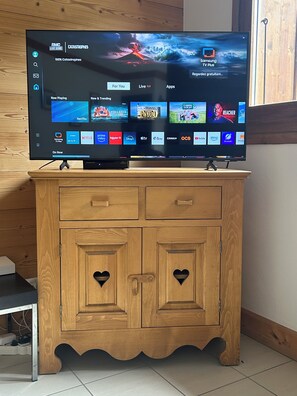 Ein Flachbildfernseher auf einer Holzkabine mit herzförmigen Ausschnitten an den Türen.