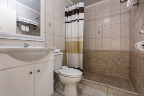 Un baño con lavamanos, inodoro y cortina de ducha blancos.