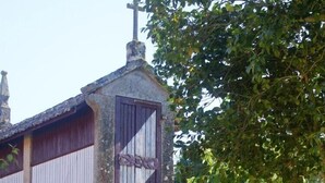 Un bâtiment en pierre avec un escalier en bois menant à une porte surmontée d’une croix.