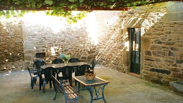Une terrasse extérieure avec des murs en pierre, une table avec des chaises et un banc.