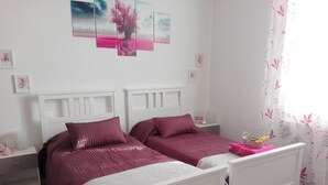 A bedroom with two beds, white headboards, and a pink and white color scheme.