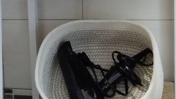 A shelf with a red towel and a white basket containing black shoes.