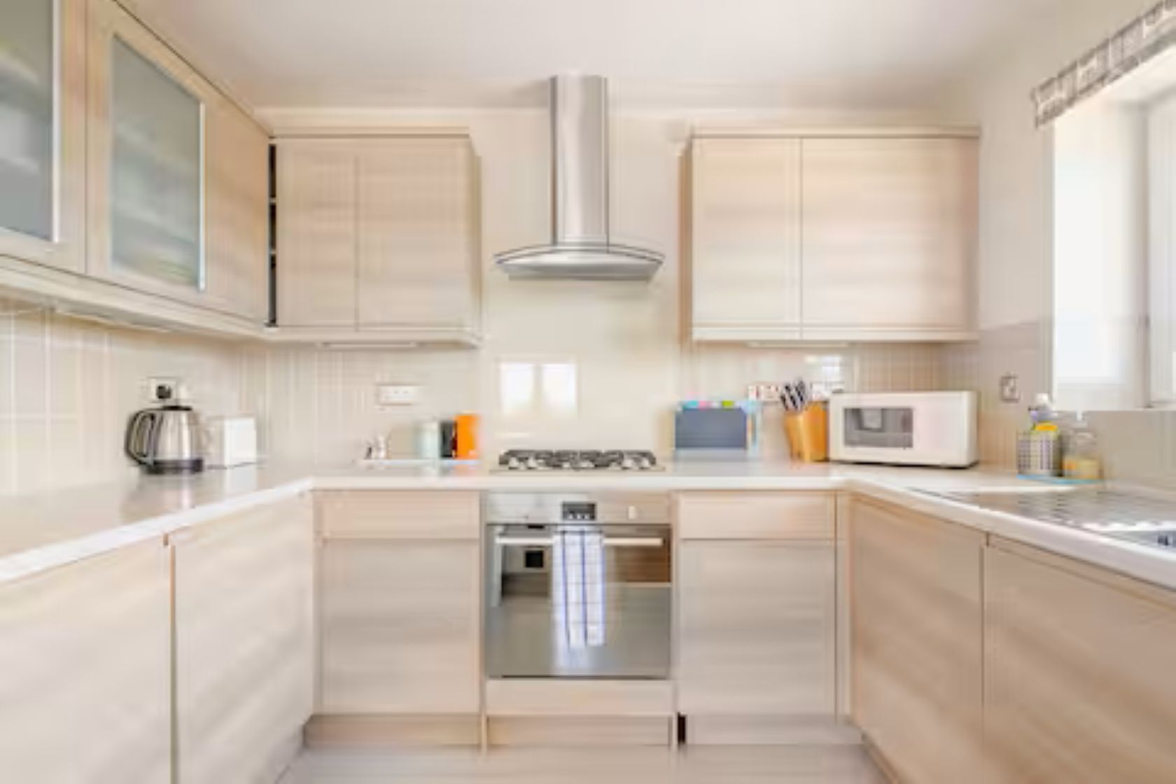 Una cucina moderna con mobili chiari in legno, elettrodomestici in acciaio inossidabile e un'isola centrale.