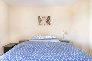 A bedroom with a bed, two nightstands, a wall-mounted artwork, and a bedside lamp. - Beautiful 2-bedroom apartment, close to Portobello Market (London)