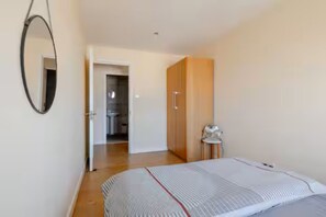 A bedroom with a bed, a wardrobe, a mirror, and a door leading to a bathroom.