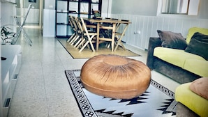 Ein modernes Wohnzimmer mit Esstisch aus Holz, einer Couch und einem dekorativen Teppich.