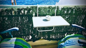 Ein Zimmer mit Meerblick, ein kleiner Tisch mit einem weißen Gegenstand und zwei gestreifte Stühle.