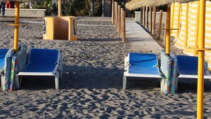 A beach with sun loungers and thatched umbrellas, a street with buildings, and a clear sky. - Luxury 3 bed apartment, on sea front, sleeps 6 (Torrox-Costa (Malaga))