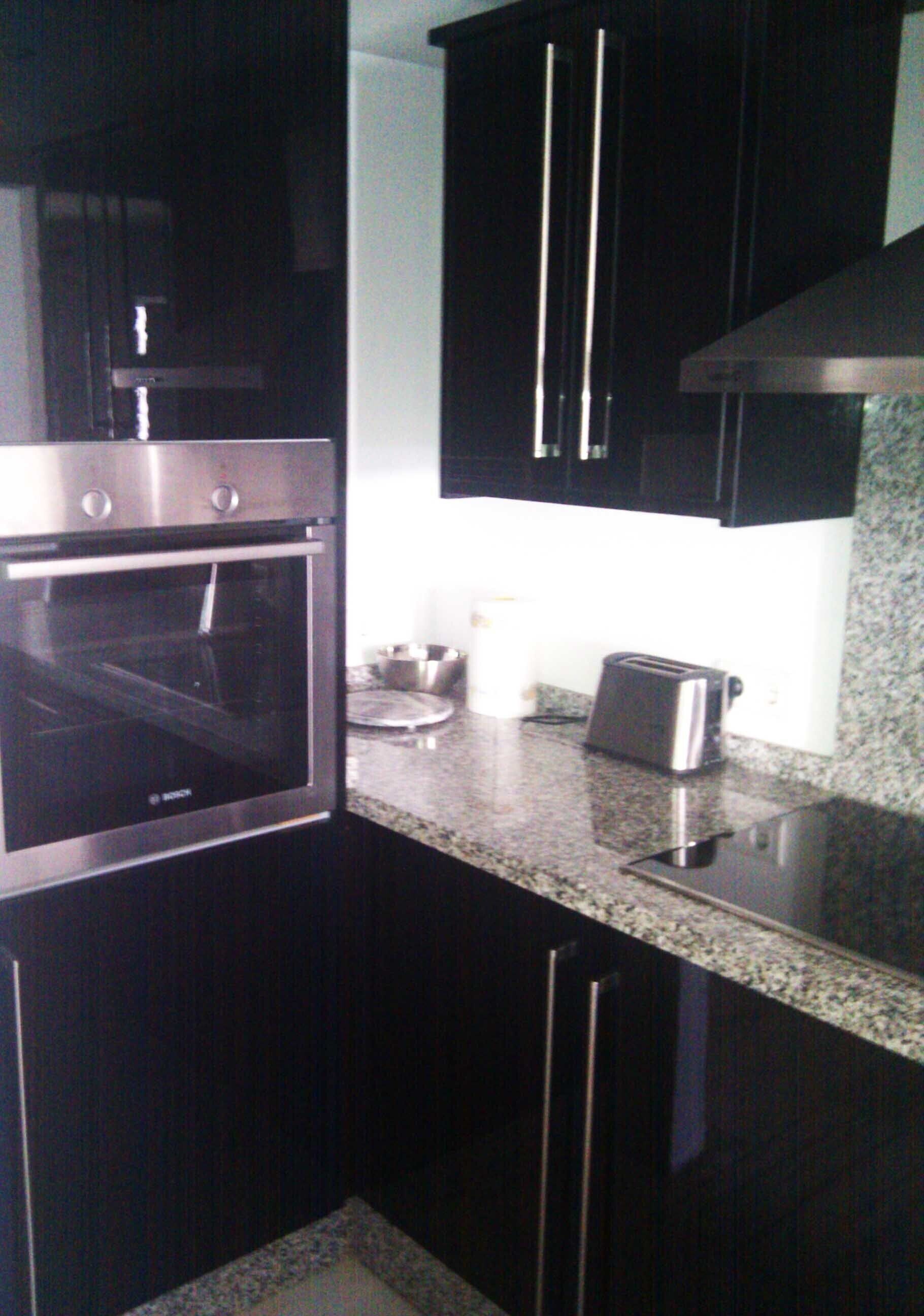 A kitchen with dark cabinets, a stainless steel oven, a toaster, and a coffee maker.