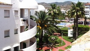 A white building with balconies, palm trees, and a red pathway. - Luxury 3 bed apartment, on sea front, sleeps 6 (Torrox-Costa (Malaga))