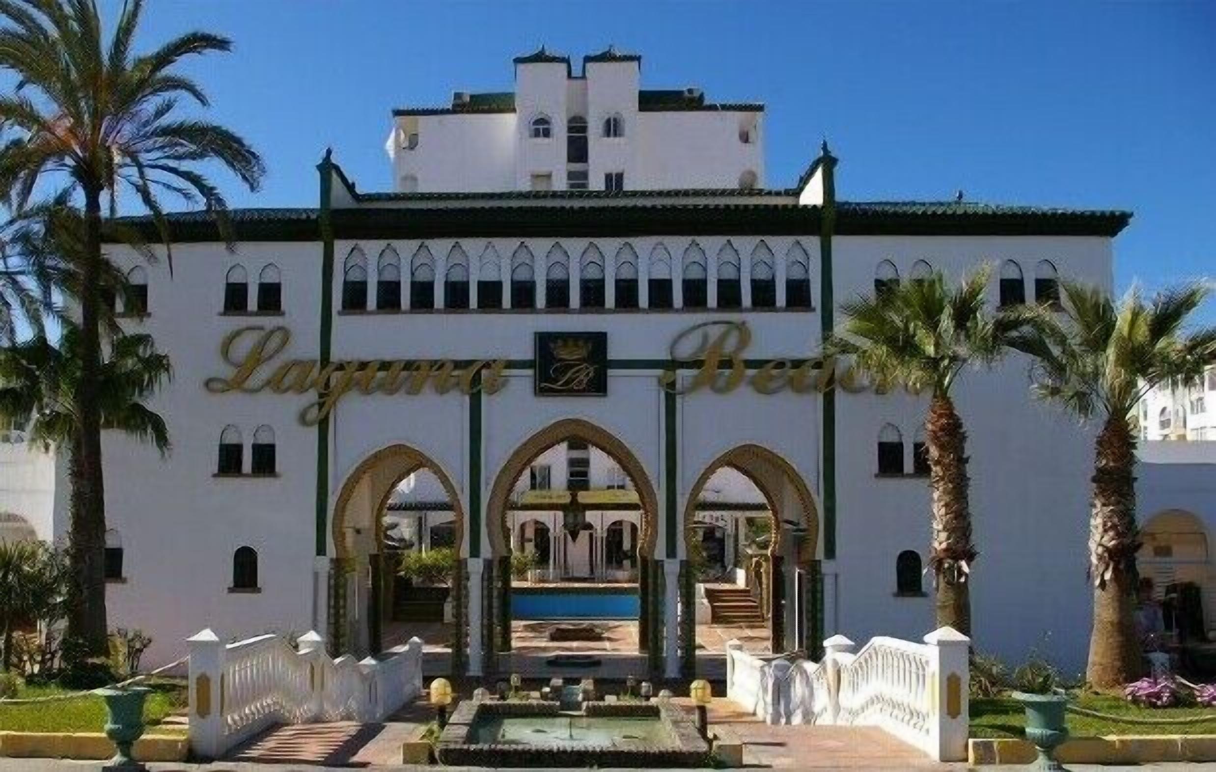 Ein Gebäude mit heller Fassade, mehreren Bögen und einem zentralen Poolbereich.