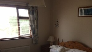 Une chambre à coucher avec un lit, une fenêtre avec des stores, une lampe et un luminaire fixé au mur.