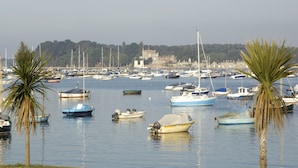 Un port de plaisance où sont amarrés différents types de bateaux, entouré de palmiers et avec un bâtiment visible au loin.
