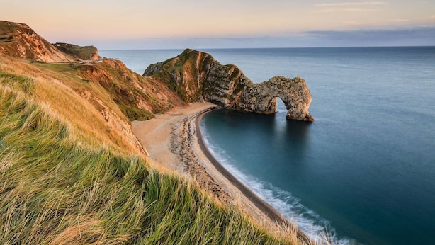 Un paysage côtier caractérisé par une formation rocheuse imposante et une plage.