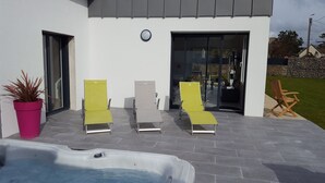 Ein moderner Außenbereich mit Whirlpool, zwei Liegestühlen und einem Blumentopf.