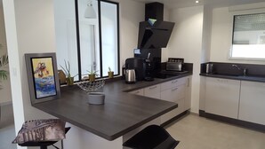 Eine moderne Küche mit dunkler Arbeitsplatte, einer Kaffeemaschine, einem Toaster und einem Spülbecken.