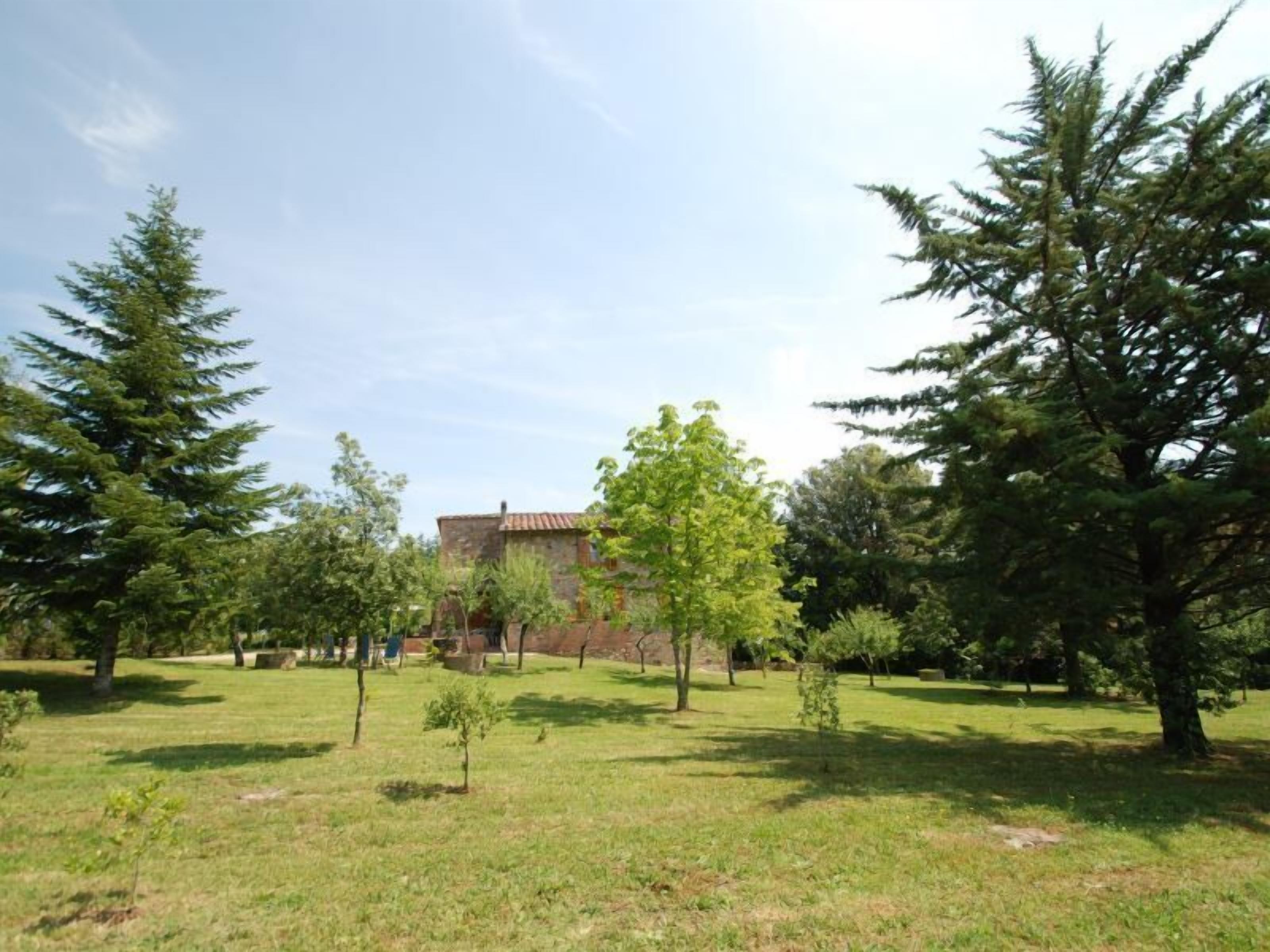 A courtyard with a building in the background, surrounded by trees and grass.