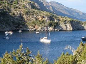 A marina with several sailboats and smaller boats anchored in calm waters, surrounded by rocky hills and sparse vegetation. - GREECE,RENT A LUXURY SAILBOAT WITH SKIPPER &CHEF🐬 (Lavrio)