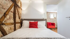 Ein Schlafzimmer mit einem Bett, einem roten Sessel und einer Steinwand.