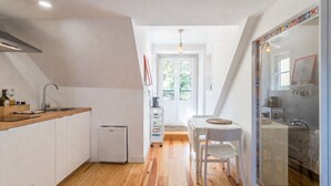 Eine kleine Küche mit Kühlschrank, Spüle und einer Essecke mit Tisch und Stühlen.