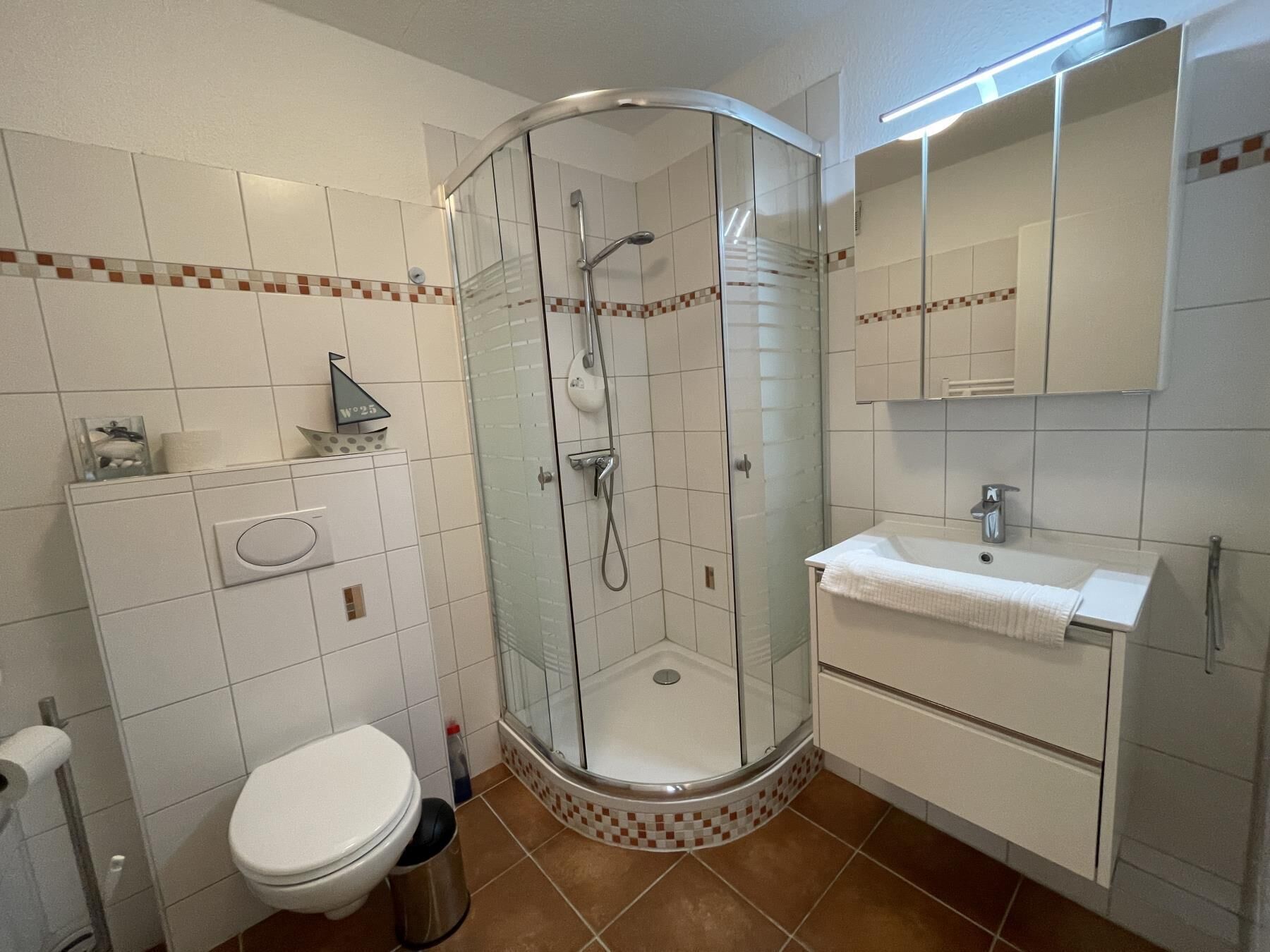 Ein Badezimmer mit Duschkabine, Toilette, Waschbecken und Spiegel.
