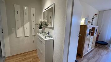 Une salle de bain moderne avec un meuble-lavabo en verre, un grand miroir et une plante en pot.