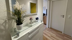Ein modernes Badezimmer mit einem Glaswaschtisch, einer Topfpflanze, einer Kerze und einem Spiegel.
