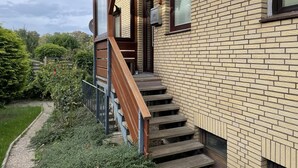 Ein modernes Haus mit Ziegelaußenwand, einer Holztreppe und einem kleinen Balkon.