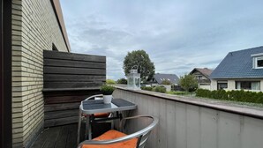 Ein Balkon mit Tisch und zwei Stühlen, einem Blumentopf und einer weißen Laterne.