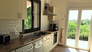 Een keuken met een ingebouwde wasmachine en droger, een raam en uitzicht op groen.