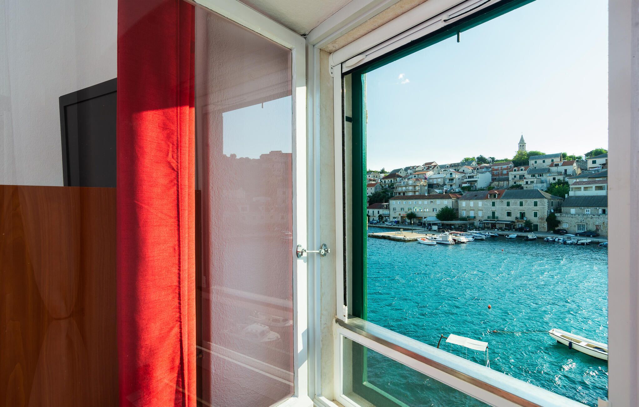A room with a view of a harbor, including boats and buildings.
