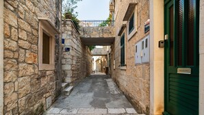 A narrow stone alleyway with a green door on the right and a sign above it. - Cozy apartment in Povlja (Povlja)