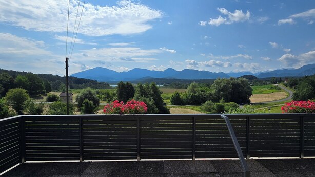 Un balcon offrant une vue sur un paysage montagneux, une route et de la verdure.