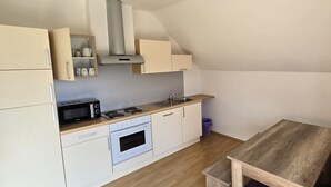 Une cuisine compacte équipée d’un four à micro-ondes, d’une cuisinière, d’un four et d’une table en bois.