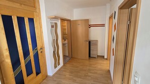 Un couloir avec des portes en bois, un miroir et un petit coin cuisine.