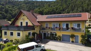 Un bâtiment jaune avec un toit recouvert de tuiles rouges, des panneaux solaires et des balcons ornés de jardinières.