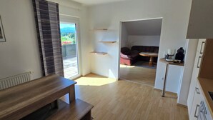 Un salon moderne avec un banc en bois, une table à manger et une vue sur un jardin, accessible par une grande porte coulissante.