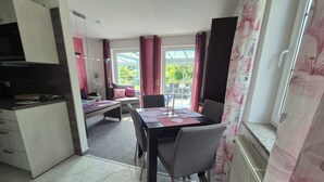 A compact kitchen with a microwave, a dining table with chairs, and a sofa with cushions. - Idyllic vacation apartment with pool, whirlpool and sauna near Leipzig (Eilenburg/ Ortsteil Behlitz)