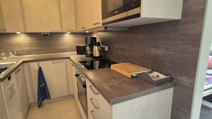 A modern kitchen with a microwave, coffee maker, and a wooden cutting board on the counter. - Idyllic vacation apartment with pool, whirlpool and sauna near Leipzig (Eilenburg/ Ortsteil Behlitz)