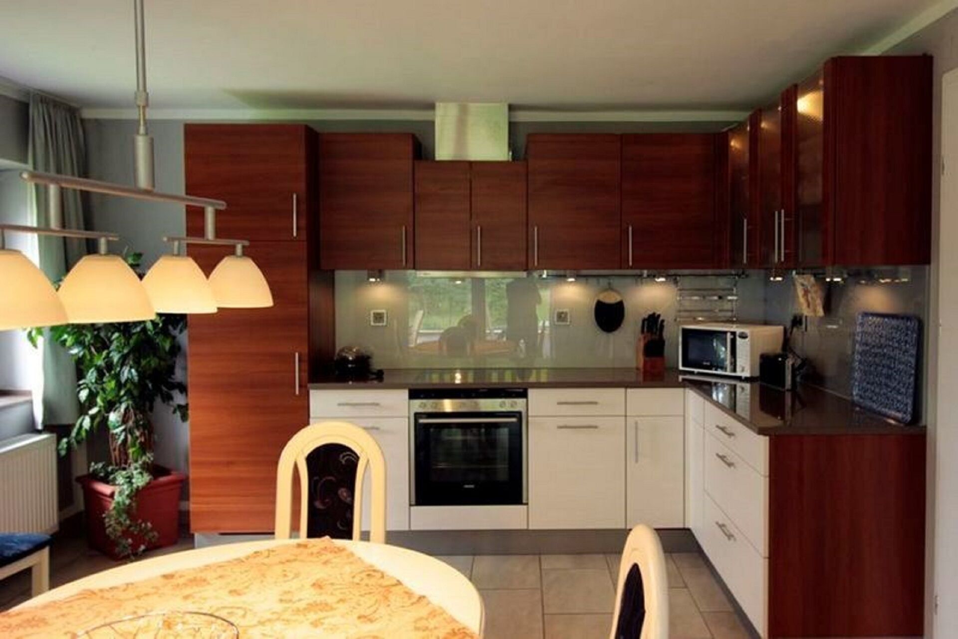 Une cuisine moderne avec des meubles en bois, un four à micro-ondes et une cuisinière. Il y a également un coin repas avec une table et des chaises.