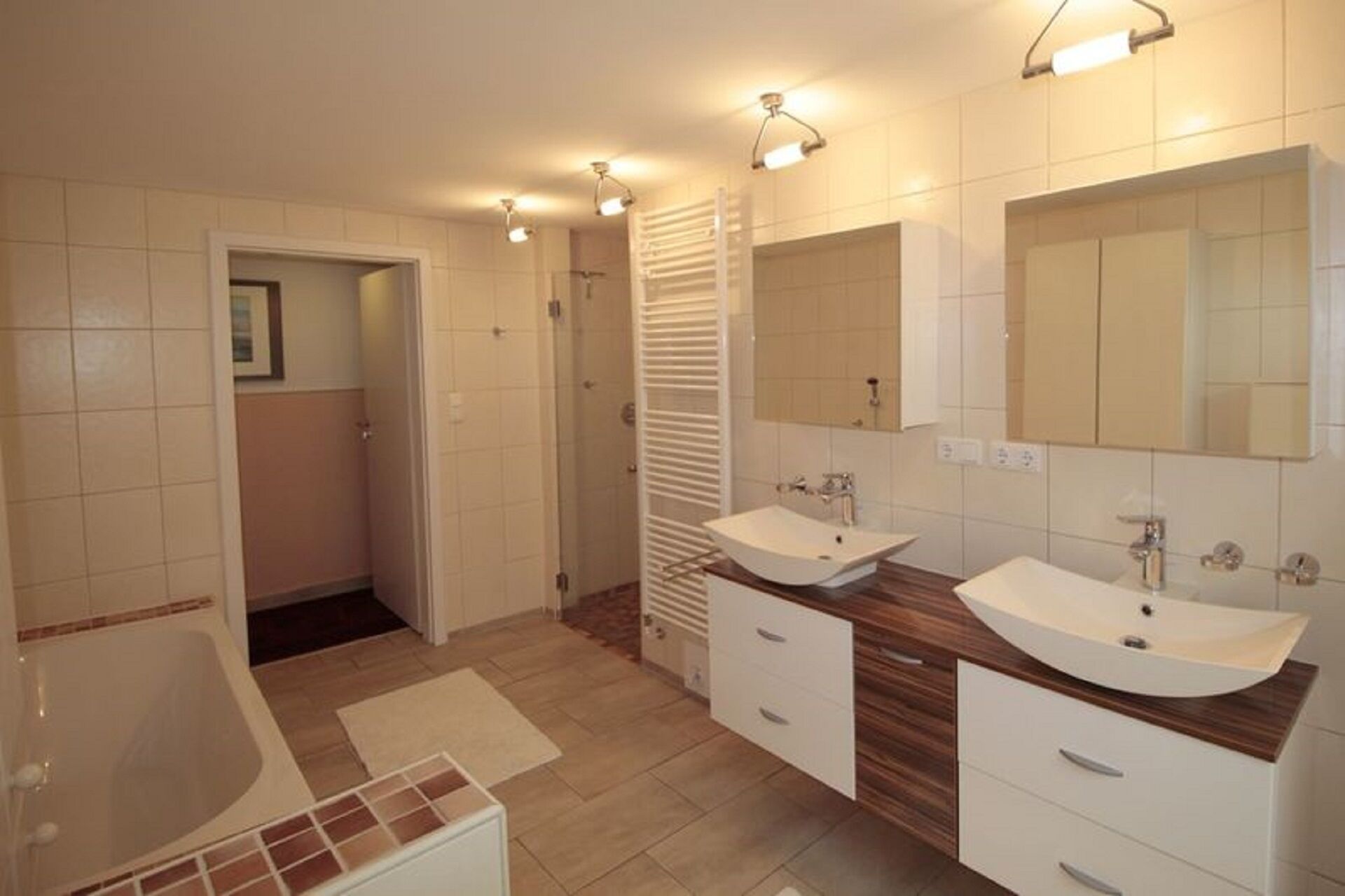 Une salle de bain moderne avec deux lavabos, une baignoire et une douche à l’italienne.