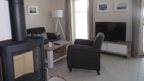 Ett vardagsrum med en öppen spis, soffa, fåtölj, TV och en lampa.