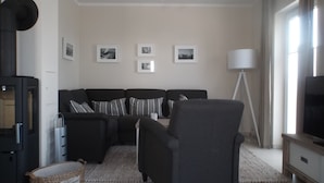 Ett modernt vardagsrum med en soffgrupp, en golvlampa och en tv.