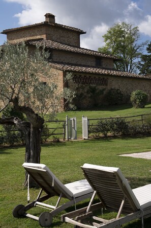 Relax in a serene outdoor setting with a traditional building, lounge chairs, and a tree.