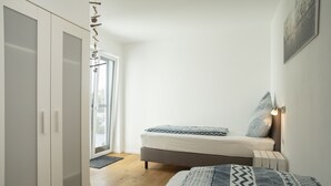 A bedroom with a bed, a wardrobe, and a door leading to a balcony.