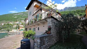 Un bâtiment à deux étages doté d’un balcon, d’un mur en pierre et offrant une vue sur un lac et des montagnes.